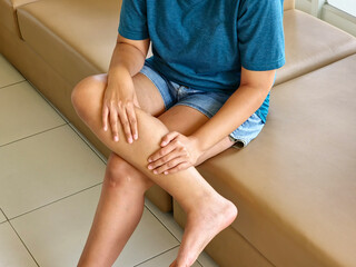 Leg pain calf area, muscle inflammation, cramp while woman sitting on sofa. Health care concept. © Tanu4869