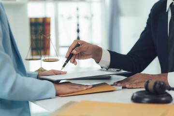 Legal Signing: A lawyer guides a client's hand as she signs an important document, symbolizing...