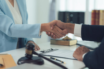 Successful Legal Partnership: A close-up shot of a lawyer and client shaking hands across a desk,...