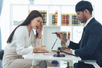 Fototapeta premium Legal Consultation: A woman sits across from a lawyer, looking worried and stressed as he speaks. The lawyer holds a pen and gavel, emphasizing the serious nature of the legal consultation.