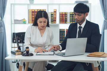 Legal Counsel Collaboration:  A male and female lawyer team works together on a case, reviewing documents and using a laptop in their modern office.  The image conveys professionalism.
