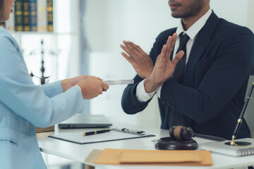 Refusal of a Bribe: Lawyer rejecting a bribe offer during a serious business meeting.  Focus on the lawyer's determined expression and the rejection of the offered item.