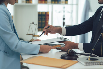Lawyer Discussing Legal Documents with Client:  A lawyer in a formal suit points to a document on a clipboard, discussing a legal matter with a client in a professional office setting.