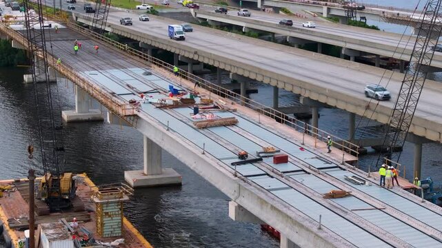 Men working at industrial construction roadworks with new bridge spans being built in Ellenton, Florida. Development of interstate transportation