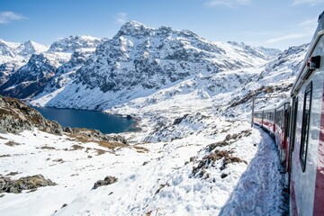 Fototapeta premium Experience the Majestic Snow-Capped Peaks and Serene Lakes on a Scenic Train Ride through a Winter Wonderland