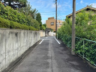 narrow street in a suburban Japanese neighborhood - one-way road between a concrete wall and a...