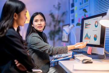 Two women are looking at a computer monitor with graphs on it