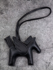Close up of black leather horse bag keychain on grey background