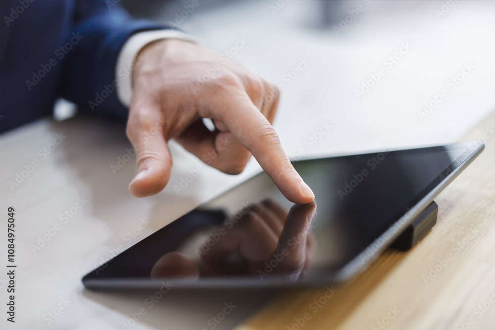 Poster man's finger engaging with a cutting-edge digital tablet screen, device situated on a desk within th