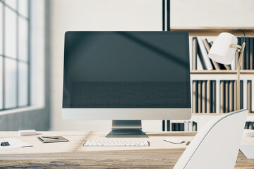 Front view on blank modern computer monitor with copyspace for your text or logo on wooden table with white keyboard and stylish lamp in sunny office with bookcase on background. 3D rendering, mockup