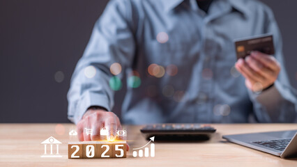 2025 year. A man is holding a credit card and a laptop