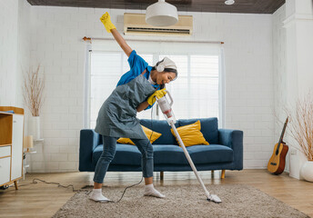 House cleaning becomes delightful Asian housewife joyfully sings using a vacuum cleaner as a...