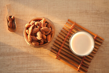 A bowl of almond milk surrounded by assorted nuts placed on a rustic wooden background