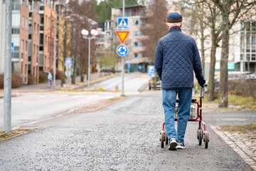 Old man with a wheeled rollator walker on the street