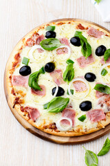 Pizza with ham, green pepper, mozzarella cheese and black olives. Wooden background.