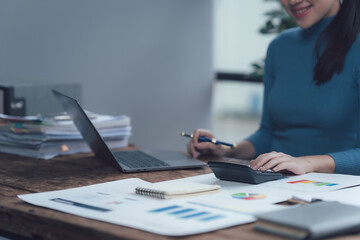 Focused and Efficient: A young businesswoman meticulously works on financial documents at her desk,...