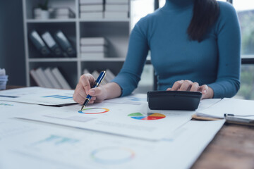 Focused on the Numbers:  A businesswoman meticulously analyzes financial charts, her concentration...
