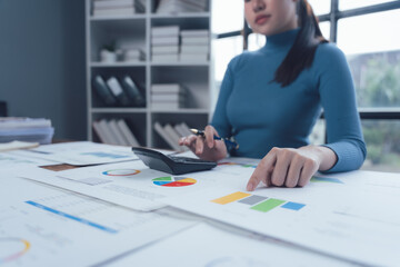 Focused on Financial Growth: An Asian businesswoman meticulously analyzes graphs and charts,...