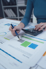 Analyzing Financial Reports: Close-up of a woman's hands meticulously reviewing financial charts...