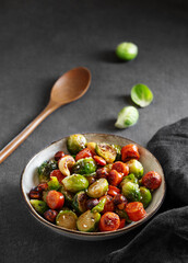 Brussels sprouts with chorizo ​​sausages, nuts and sesame seeds. Concept nutritious asian dish in a bowl on a dark background