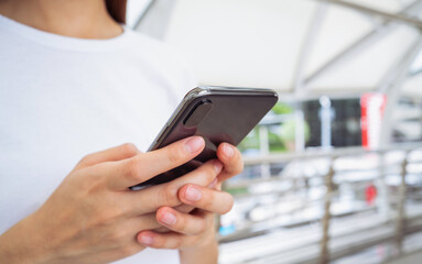 Woman holding smartphone while walking in the urban city. The concept of using the phone is essential in everyday life.