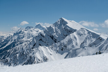 Obraz premium Snow-covered mountain range under a clear blue sky with distant peaks in the afternoon