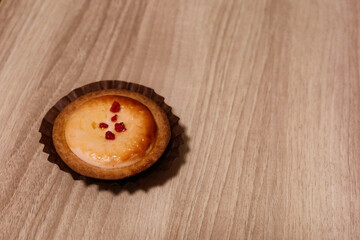 close up of baked cheese tart with raspberry as toppings on a wooden table with copy space