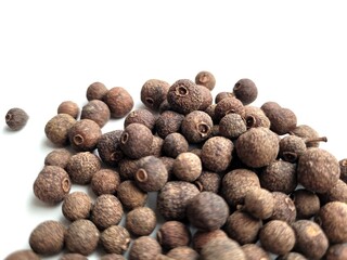 Portion of aromatic allspice seeds on a white background.