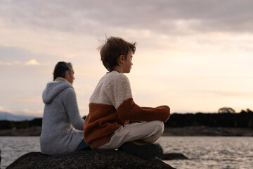 Boy with his mother meditating at sunrise in nature