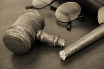 Broken wooden judge gavel with legal book and eyeglasses. I