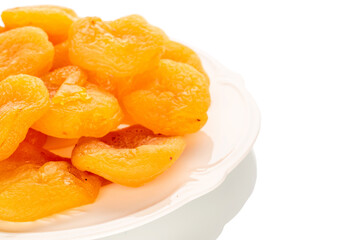 Sweet dried apricots on a ceramic plate, close-up, isolated on a white background.