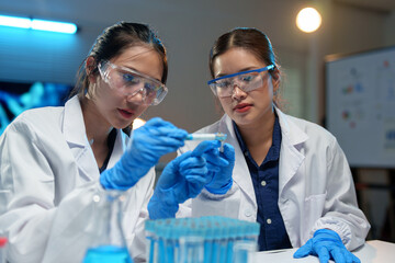 Medical laboratory Biology research development Advanced equipment Two female scientists working using test tubes blue solution Analyze biochemical samples in a medical science laboratory.