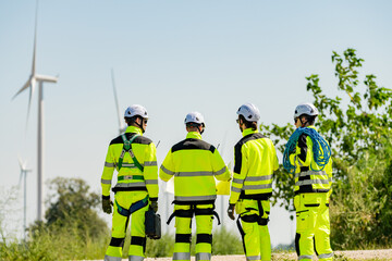 Four young male wind farm engineers work inspecting field systems.Wind turbine engineer inspection and wind turbine inspection progress at construction site.