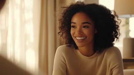 A woman in discussion while in a bright office smiling softly as she uses her hands to explain a complex idea