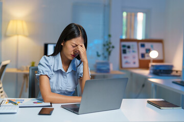 Stressed, tired, sleepy businesswoman bored from sitting at a desk for long hours and having office syndrome while working with laptop and financial paperwork. Office marketing.