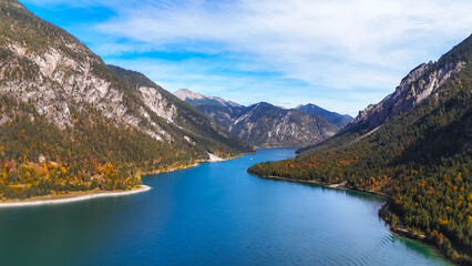 Exploring the serene beauty of a river in Europe. Travelers admire the breathtaking river near mountains during a sunny day in Europe, surrounded by lush greenery.