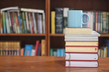 stack of books on wooden table and glass on top of books on blurred background. space for text, education, school