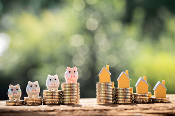 Home model and piggy bank put on top the stack gold coin with compare put on the wood in the public park, Saving money for buy house or loan for plan business investment of real estate concept.
