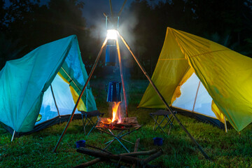 camping tent in the forest with green trees, camping in the forest at night, Small gas lantern on green grass