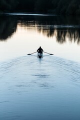 Silhouette of person rowing on a calm river.
