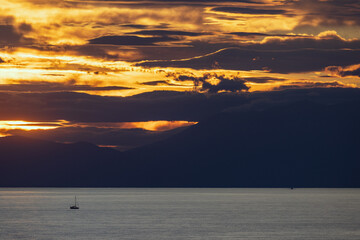This image captures a breathtaking sunset over Aegean sea in Greece, with dramatic clouds casting...