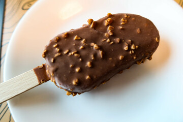 close up of chocolate chip peanut ice stick ice cream stick bar dessert on a white plate 