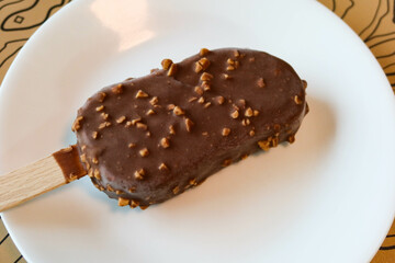 close up of chocolate chip peanut ice stick ice cream stick bar dessert on a white plate 