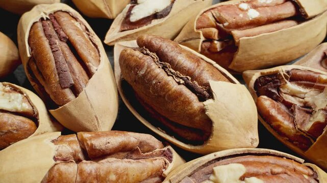 Cracked pecans rotating. Group of unpeeled pecans. Delicious nuts. Vegan organic food. Healthy nutrition. Close-up in 4K, UHD