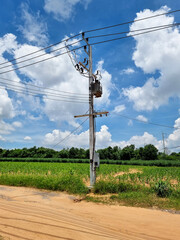 Obraz premium The Oil-immersed Transformer installed by Pole Mounted for utility on clouds in the blue sky background.