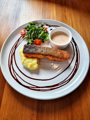 Vertical shot of Grilled salmon steak with white wine sauce, mashed potatoes and salad