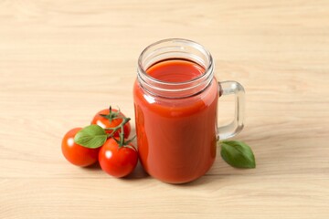 Tomato juice in a glass and fresh tomatoes on the table