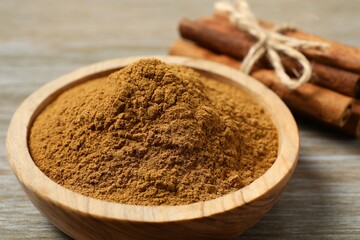 Cinnamon sticks and cinnamon powder in a bowl on a wooden background