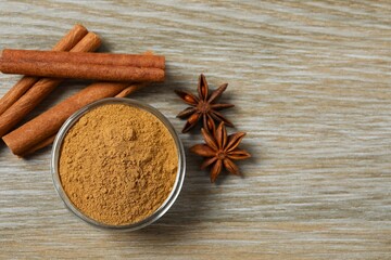 Aromatic cinnamon sticks, cinnamon powder and anise stars on a wooden background
