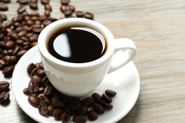 Cup of coffee and coffee beans on wooden background
